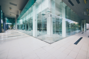 Polished white commercial floor tiles in a modern building entrance with floor-to-ceiling glass walls