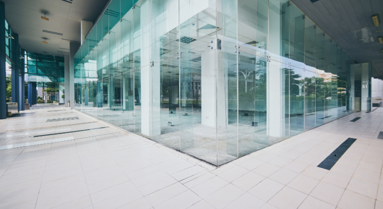 Polished white commercial floor tiles in a modern building entrance with floor-to-ceiling glass walls
