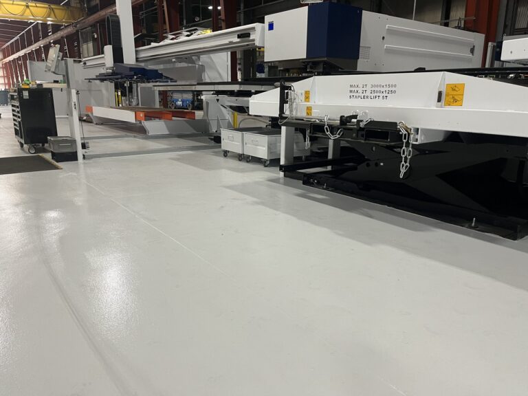 Finished gray resinous floor beside a sheet-metal punching machine and its loading table, American Steel and Aluminum, Auburn, MA