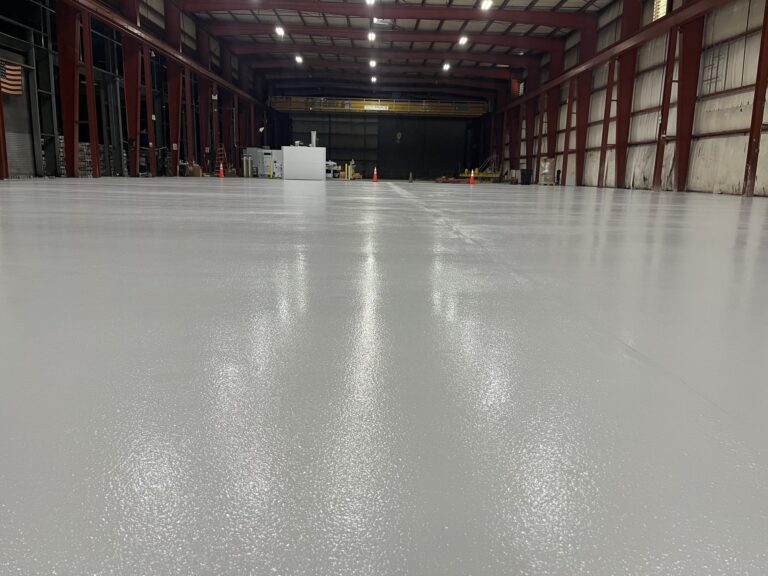 Long finished fabrication bay with a gray resinous floor and a US flag on the wall, American Steel and Aluminum, Auburn, MA
