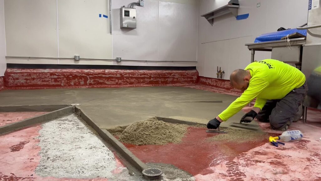 Topcoat installer troweling material between screeds at Commonwealth Kitchen, Dorchester, MA