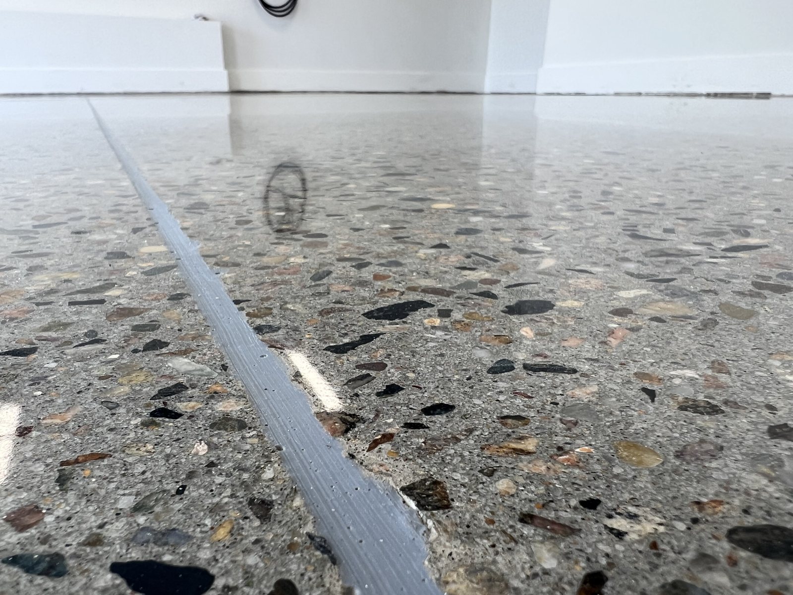 Filled saw-cut control joint through a polished exposed-aggregate concrete floor