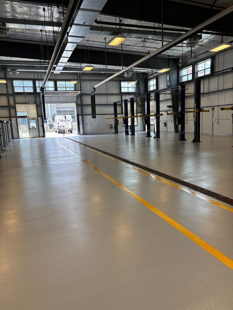 Finished light gray urethane cement floor with yellow and black safety lines in automotive service bays, Essex North Shore Agricultural & Technical School automotive shop, Danvers, MA