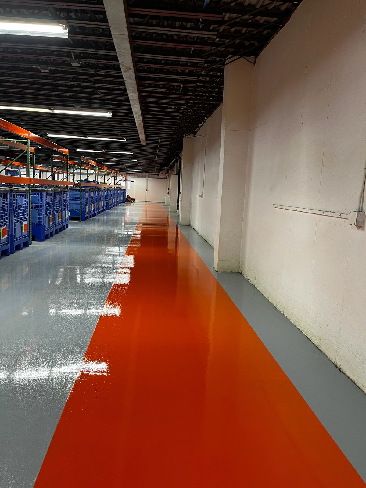 Long orange aisle on a gray floor running along racking, High Purity New England, Smithfield, RI