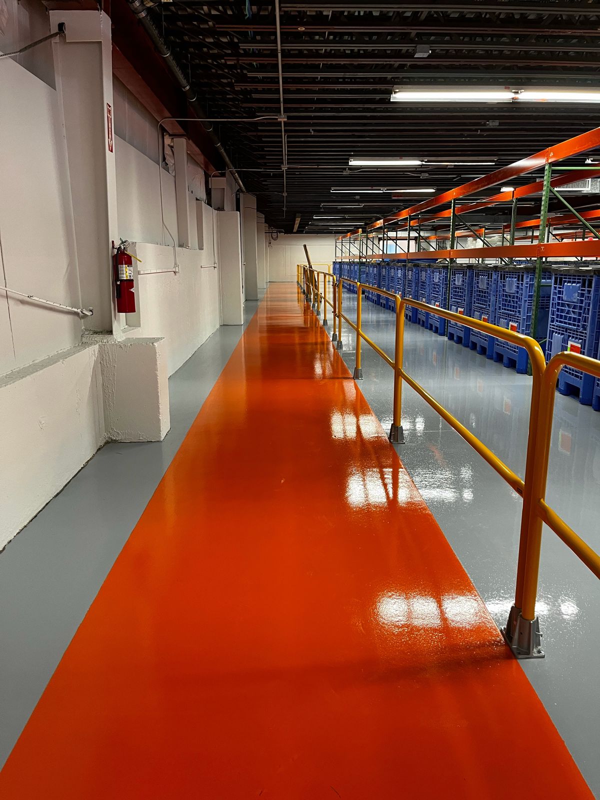 Orange walkway beside a yellow guardrail and racking on a gray floor, High Purity New England, Smithfield, RI