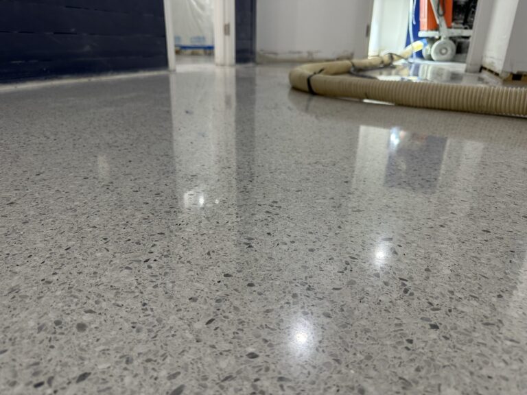 Polished cement terrazzo hallway floor beside a navy wall, with a vacuum hose in the background, Ardex cementitious terrazzo, Hyannis office