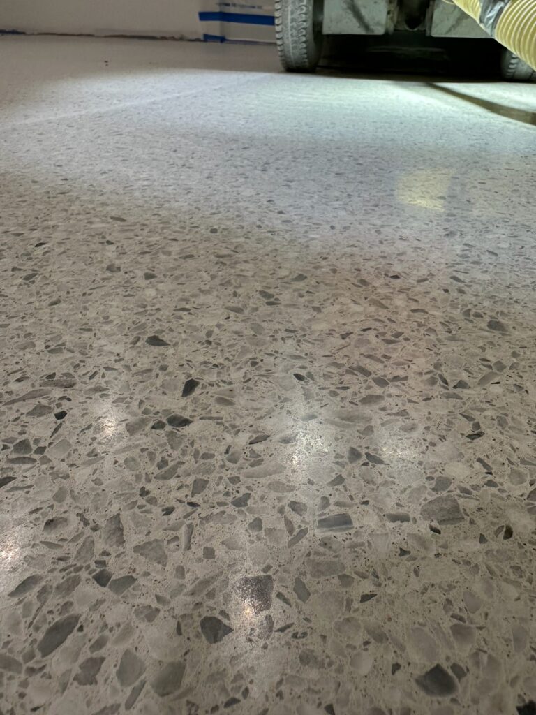 Close-up of polished cement terrazzo with larger aggregate, grinding equipment in the background, Ardex cementitious terrazzo, Hyannis office