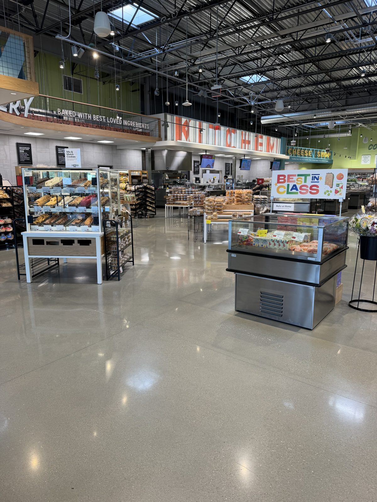 Retail & Grocery Flooring 5 Polished concrete sales floor in the bakery area with bread display cases and a refrigerated case, and the kitchen counter behind, at Whole Foods Market, Seekonk, MA